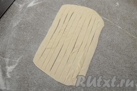 Острым ножом раскатанное тесто нарезать на полоски шириной 5-7 миллиметров, не дорезая до краёв прямоугольника примерно по 1 сантиметру. То есть полоски будут внутри прямоугольника из теста.