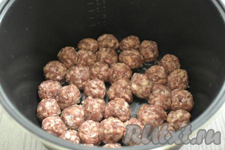 В съёмную чашу мультиварки вливаем растительное масло. Включаем мультиварку на режим "Жарка" на 12 минут. Когда прозвучит звуковой сигнал о том, что масло нагрелось, выкладываем в чашу сформированные фрикадельки в один слой. Обжариваем их до подрумянивания с двух сторон (в течение 5-6 минут с каждой стороны).