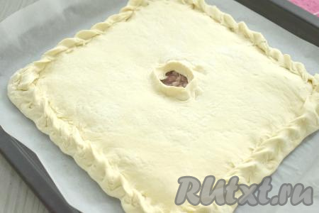 Затем второй пласт теста на присыпанной мукой поверхности раскатываем в квадрат со стороной 24 сантиметра. Тесто с начинкой накрываем вторым раскатанным пластом теста, тщательно скрепляем края пирога. В центре верхнего пласта теста делаем отверстие для выхода пара.