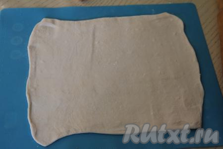 Слоёное тесто выложить на рабочую поверхность, слегка припылённую мукой, и раскатать до толщины ориентировочно 2-3 миллиметра.