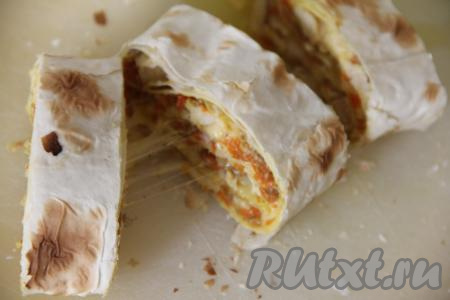 Готовый рулет из лаваша достать из духовки, убрать фольгу. Переложить рулет на разделочную доску и нарезать на кусочки. При нарезании горячего рулета сыр приятно тянется. Начинка из курицы и овощей получается очень аппетитной.&nbsp;