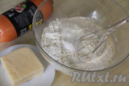 Всыпать в миску разрыхлитель и начать добавлять постепенно муку, вмешивая каждую порцию муки в тесто венчиком. Итоговое тесто должно получиться в меру густым, напоминающим сметану средней жирности.