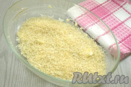 Рис хорошо промываем под проточной водой, лишнюю воду сливаем. В форму для запекания поверх лука и чеснока ровным слоем выкладываем подготовленный рис.