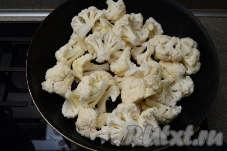 В сковороду влить растительное масло, разогреть, выложить цветную капусту. Влить 2-3 столовых ложки воды.