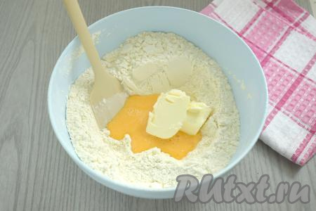 В миску с мучной смесью вливаем яйцо, взбитое вилкой, добавляем кусочки сливочного масла комнатной температуры.