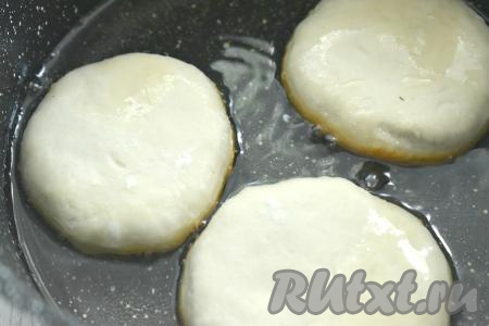 В глубокой сковороде разогреваем достаточное количество растительного масла. Заготовки беляшей выкладываем в горячее масло отверстием вниз. Масло должно доходить практически до середины беляшей. Жарим на огне ниже среднего до подрумянивания слоёного теста с двух сторон (примерно по 3,5-4 минуты с каждой стороны).