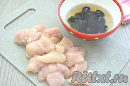 Куриное мясо моем, обсушиваем, нарезаем на небольшие кусочки. Чернослив промываем водой, после этого выкладываем в достаточно глубокую ёмкость, заливаем кипятком, оставляем на 10 минут, затем воду сливаем.