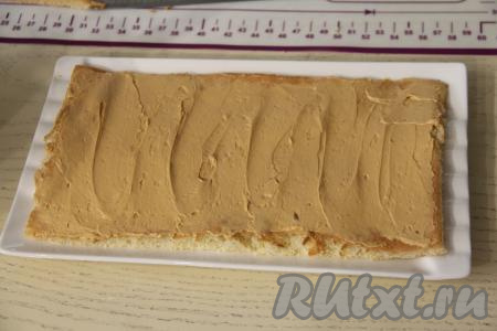 После того как коржи остынут и крем из масла с варёной сгущёнкой будет готов, можно приступать к сборке торта "Золотой ключик". Для этого на плоскую тарелку подходящего размера нужно выложить первый корж, смазать его частью крема.