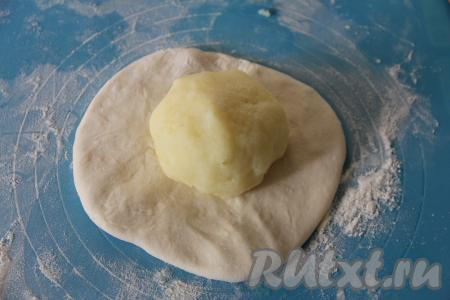 На припылённой мукой поверхности вначале одну часть теста раскатать скалкой в небольшой круг, в середину выложить картофельный шарик.