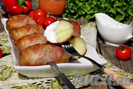Готовую картошку в беконе переложить с мангала на тарелку для подачи, убрать шампуры. Подать к столу в горячем виде, дополнив любимым соусом.&nbsp;