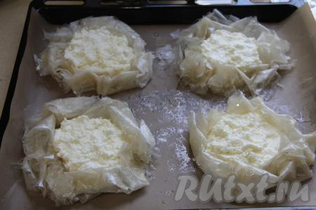 Переложить сформированную ватрушку с творогом на противень, застеленный ковриком (или бумагой) для выпечки. Аналогично сформировать ещё 3 ватрушки из оставшихся листов теста фило и начинки из творога. 