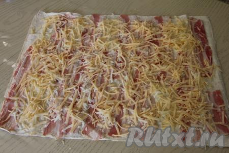 Сыр натереть на крупной тёрке и равномерно разложить поверх бекона.