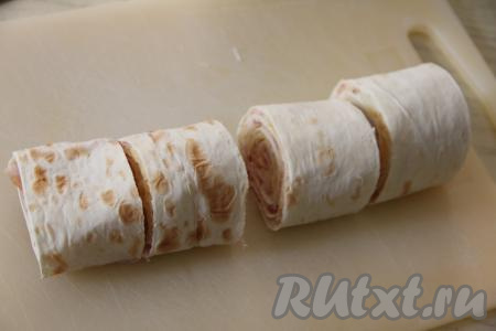 Нарезать рулет на кусочки шириной по 5 сантиметров. Получится 8 рулетиков из лаваша с начинкой из сыра и бекона.