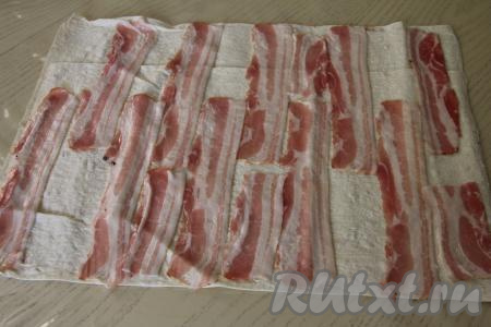 Лист лаваша развернуть, отрезать прямоугольник размером 40 сантиметров на 50 сантиметров. Выложить полоски бекона на лаваш.