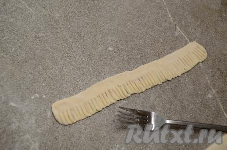 На одной длинной стороне полоски из теста при помощи вилки сделать зазубренки. Если вилка пристаёт к тесту, тогда периодически можно окунать кончики вилки в муку.