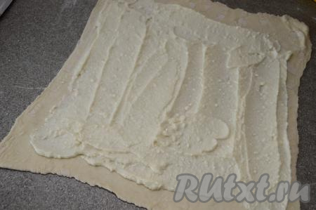 ​​​​Отступая с длинных сторон раскатанного теста по 1 сантиметру, а с коротких сторон - по 2 сантиметра, равномерно смазать тесто творожной массой.
