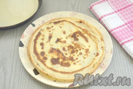 Приступаем к выпечке блинов. Поверхность сковороды (я использовала сковородку диаметром 17 сантиметров) смазываем растительным маслом, разогреваем на достаточно сильном огне, уменьшаем огонь до среднего. Вливаем в сковороду примерно половину половника теста, сразу равномерно распределяем тесто по дну сковороды. Жарим блинчик на среднем огне до зарумянивания с двух сторон (примерно по 1 минуте с каждой стороны), затем перекладываем на тарелку. Постепенно жарим все блинчики из оставшегося теста, смазывая сковороду маслом только по мере необходимости. Периодически тесто в миске перемешиваем, чтобы оно не оседало на дно.