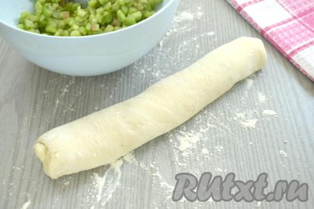 На столе, присыпанной мукой, разморозившееся слоёное тесто сворачиваем в плотный рулет.