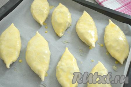 Сформированный пирожок из слоёного теста выкладываем "швом" вниз на противень, застеленный ковриком (или пергаментом) для выпечки. Аналогично формируем и выкладываем на застеленный противень на небольшом расстоянии друг от друга все пирожки с ревенем. В небольшой миске соединяем яичный желток и молоко, перемешиваем вилкой до однородности, получившейся смесью с помощью силиконовой кисточки смазываем поверхность пирожков. Я сформировала 8 пирожков.