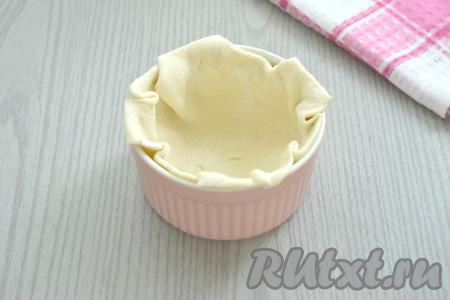 На присыпанной мукой поверхности вначале одну часть теста раскатываем в квадрат со стороной 15 сантиметров. Раскатанное тесто выкладываем в смазанную сливочным маслом формочку. Края теста можно срезать. Аналогично формируем ещё 3 формочки с тестом.
