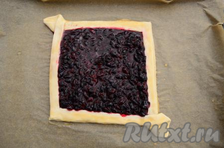 Яичный желток в небольшой ёмкости взбить вилкой до однородности. С помощью силиконовой кисточки смазать бортик пирога взбитым желтком. На дно пирога аккуратно, стараясь не испачкать бортик, выложить ягодную начинку, разровнять её.