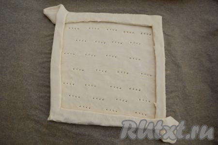 При помощи вилки наколоть дно заготовки пирога. Накалывать вилкой тесто нужно для того, чтобы оно сильно не поднималось во время выпечки и начинка не вытекала.