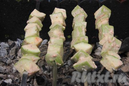 Пока кабачки маринуются, подготовить угли в мангале. Угли должны быть раскалёнными, но прямого огня быть не должно. Замаринованные кабачки нанизать на шампуры. Выложить шампуры с кабачками на мангал с раскалёнными углями.