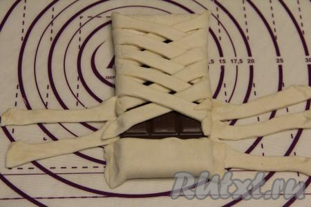 Завернув шоколад в косичку до середины, подвернуть второй более узкий край теста на шоколад, хорошо прижать края.&nbsp;