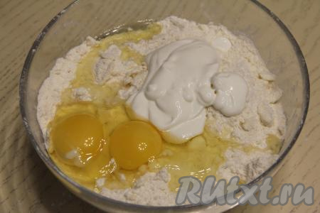В миску с получившейся крошкой добавить яйца и сметану, перемешать. Влить 1 столовую ложку холодной воды, собирая песочное тесто в шар. Если тесто не будет собираться в шар, тогда добавьте ещё 1 столовую ложку холодной воды и хорошо вмешайте её, собирая тесто в шар.