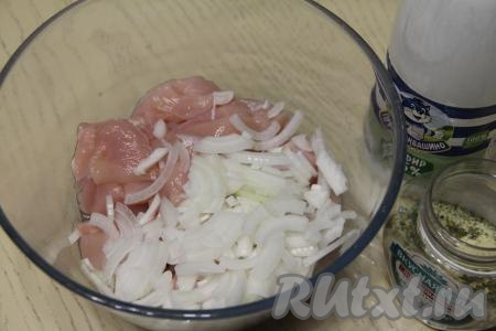 В миску выложить кусочки мяса курицы и лук, нарезанный на полукольца.