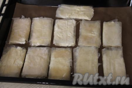 Начиная от края с начинкой, сделать несколько оборотов теста с начинкой, формируя пирожок в виде конвертика. Заготовку пирожка с творогом из теста фило выложить на противень, застеленный ковриком (или пергаментом) для выпечки. Аналогично сформировать ещё 10 заготовок пирожков.