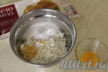 Для получения начинки для пирожков нужно соединить в достаточно глубокой миске творог, сахар и ванильный сахар, перетереть вилкой до однородности. 1 яйцо разделить на белок и желток. В миску с творожной массой добавить белок (желток в дальнейшем будем использовать для смазывания пирожков) и 1 сырое яйцо.