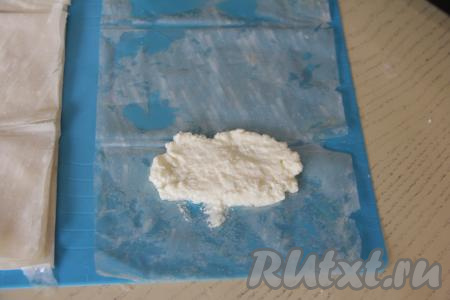 Ближе к одному из узких краёв, обязательно отступая от краёв теста, выложить 1 столовую ложку без горки творожной начинки.&nbsp;