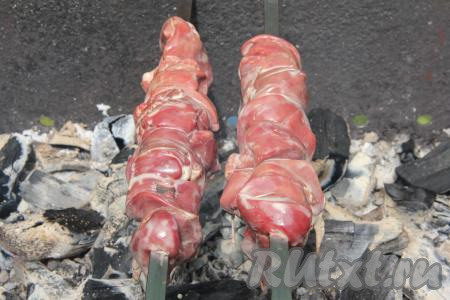 Нанизать замаринованную куриную печень на шампуры и поместить на мангал с раскалёнными (седыми) углями, прямого огня быть не должно. Если не хотите жарить на шампурах, можете выложить кусочки печени на решётку мангала.