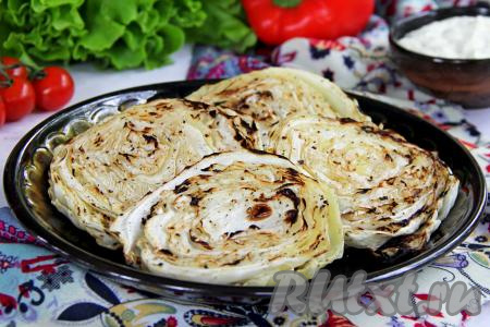 Подгоревшие крайние листочки можно убрать. Переложить вкусные, ароматные стейки из капусты на тарелку и подать к столу в качестве гарнира к мясу, дополнив соусом на ваш выбор.