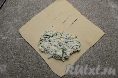 Начинку зрительно разделить на 4 равных части (то есть по количеству слоек, которое мы планируем формировать). Ближе к одному углу квадрата сделать 3-4 разреза ножом. В углу, противоположном углу с разрезами, разместить одну часть начинки, отступая от краёв теста примерно по 1 сантиметру.