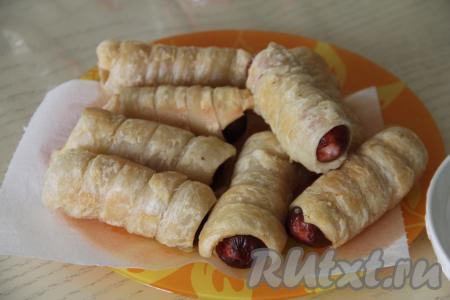 Готовые сочные сосиски, покрытые воздушным слоёным тестом, достать из мультиварки и переложить на бумажные салфетки, чтобы убрать лишний жир. Постепенно пожарить все сосиски в тесте.