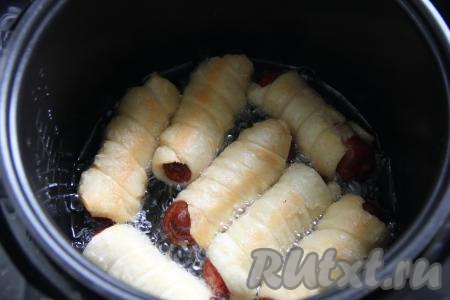 Не закрывая крышку мультиварки, жарить сосиски в тесте, периодически переворачивая, минут 10 (до золотистости слоёного теста со всех сторон).