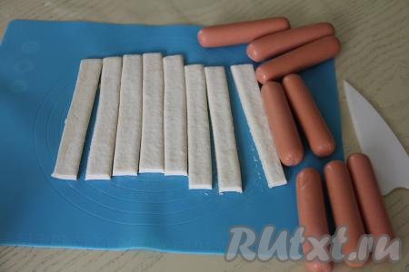 Сосиски очистить от слюды. Тесто, не раскатывая, нарезать на 8 одинаковых полосок.