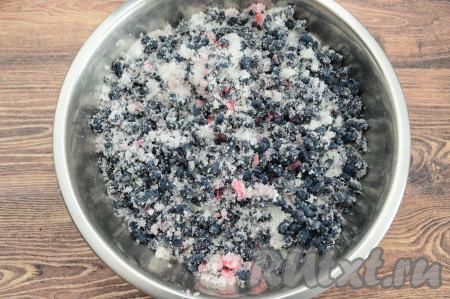 В миску с жимолостью всыпать сахар, аккуратно перемешать (можно просто аккуратно потрясти миску), смешивая ягоды с сахаром. Оставить на 40-50 минут, в течение этого времени 2-3 раза можно ещё раз перемешать (или потрясти миску).