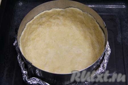 Выложить тесто в разъёмную форму для выпечки диаметром 20 сантиметров, сформировать ровное дно и достаточно высокие бортики. Я в качестве формы использовала разъёмное кулинарное кольцо диаметром 20 сантиметров, а дно сформировала из пергамента и фольги, сложенной в несколько слоёв. 