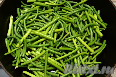 На сковороде немного разогреть 3 столовых ложки растительного масла, выложить нарезанные чесночные стрелки.&nbsp;Жарить стрелки на среднем огне 5 минут, перемешивая их примерно через каждую минуту, чтобы они не подгорели. На этом этапе я не накрываю сковороду крышкой.