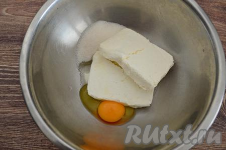 В миску всыпать сахар, выложить творог, вбить сырое яйцо.