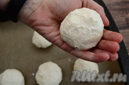 По прошествии 10 минут зрительно разделить творожно-манное тесто на равные части (я разделил на 6 частей). Из каждой части теста влажными руками сформировать округлый сырник, выложить на противень, застеленный бумагой для выпечки.