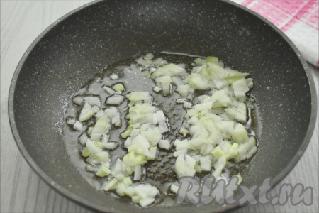 Разогреваем в сковороде растительное масло, выкладываем очищенный и достаточно мелко нарезанный лук, обжариваем его до золотистости (в течение 4-5 минут) на среднем огне, иногда перемешивая.