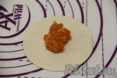 На рабочей поверхности, присыпанной мукой, раскатать тесто в тонкий пласт. Вырезать кружочки диаметром 10 сантиметров. В центр каждого кружка выложить 2 чайных ложки начинки из абрикосов.&nbsp;