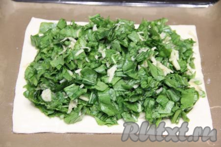 Тесто у меня было в двух пластах. На припылённом мукой столе один пласт слоёного теста&nbsp; раскатать до толщины 3 миллиметра. Выложить раскатанный пласт на противень, застеленный ковриком (или бумагой) для выпечки. Разложить на тесте всю начинку из щавеля и яблок, немного отступив от краёв пласта теста.