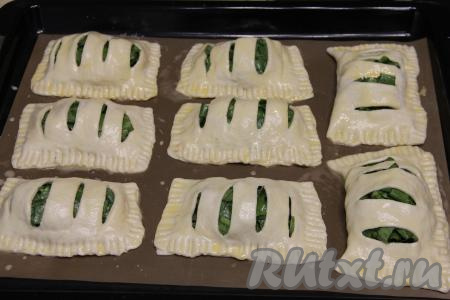 Взбить вилкой в небольшой ёмкости яичный желток. При помощи силиконовой кисточки смазать все заготовки слоёных пирожков взбитым желтком.