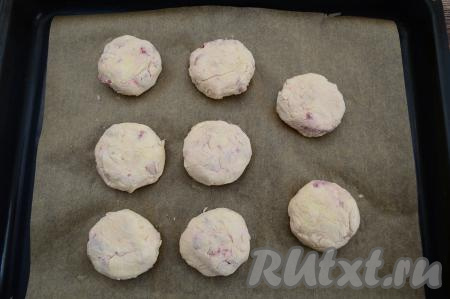 Сформированный творожно-клубничный сырник выложить на противень, застеленный пергаментом. Аналогично сформировать, обваливая в муке, ещё 7 сырников, выложить их на противень на небольшом расстоянии друг от друга. Таким образом, всего у меня получились 8 сырников.