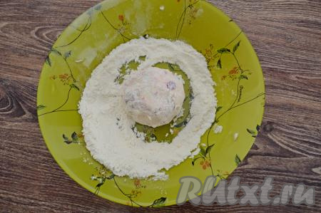 Зрительно разделить творожно-клубничное тесто на 8 равных частей. Руками, смоченными водой, взять одну часть теста, сформировать округлый сырник. Формируя сырник, старайтесь, чтобы ягоды не выступали наружу. На плоскую тарелку насыпать немного муки. Обвалять сырник со всех сторон в муке.